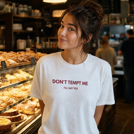 Don't Tempt Me I'll Say Yes tee worn at a bakery counter